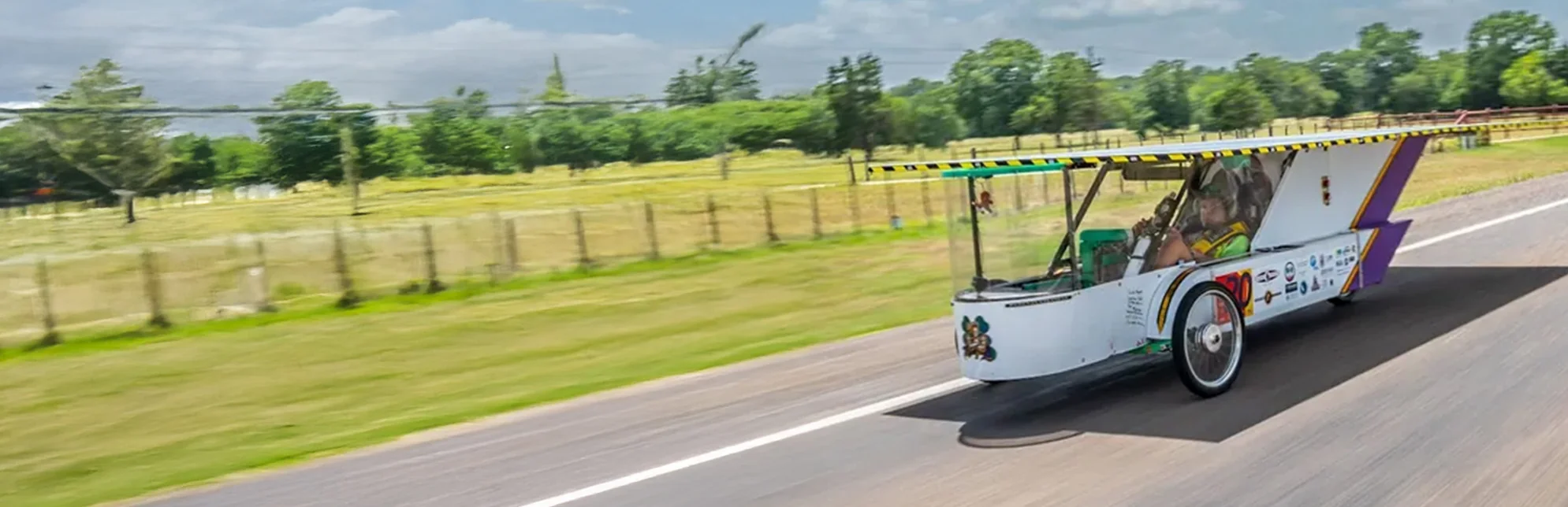 ALSET Paladins solar car racing along a tree-lined road